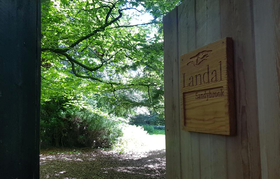 Sandy Brooks Holiday Park Sign—wooden door opens onto a snowy forest