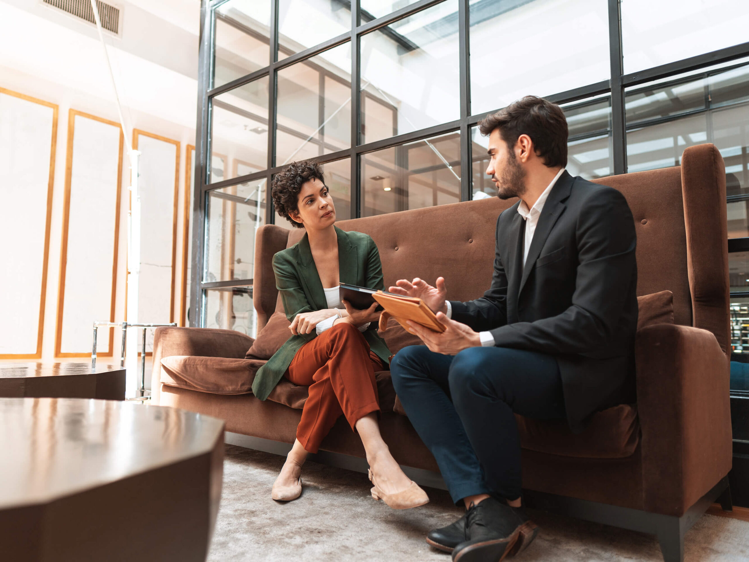 two people sitting on a sofa talking to each other